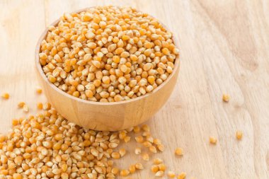 Ahşap masa üzerinde Mısır tohumları ile ahşap kase.