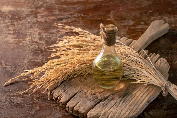 Şişe pirinç kepek yağı ve ahşap arka plan üzerinde unmilled pirinç