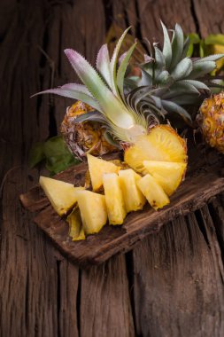 Ananas dilimleri ve eski ahşap arka plan üzerinde kabuklu ananas