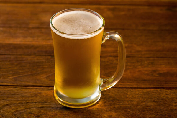 Mug of beer on wooden table.