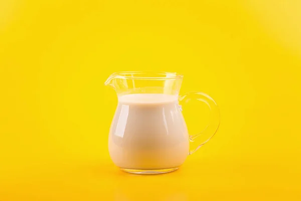 明るい黄色の背景にミルクの水差し — ストック写真