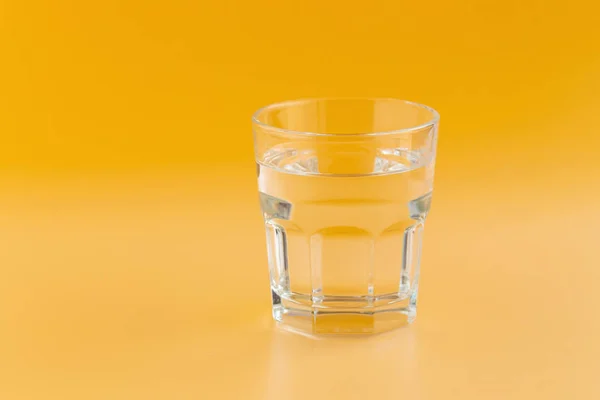 Acqua pura in un bicchiere su fondo arancione — Foto Stock