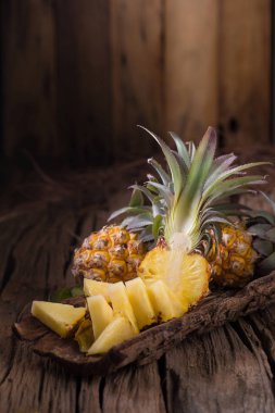 Ananas dilimleri ve eski ahşap arka plan üzerinde kabuklu ananas