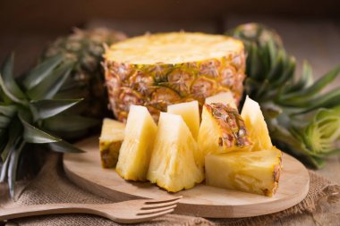 Ananas dilimleri ve eski ahşap arka plan üzerinde kabuklu ananas