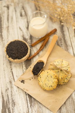 Susam kurabiye, susam ve siyah ahşap zemin üzerine süt