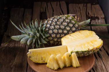 Ananas dilimleri ve eski ahşap arka plan üzerinde kabuklu ananas