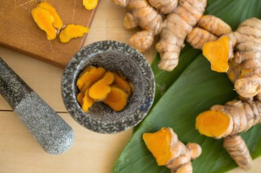 Taze zerdeçal ve zerdeçal dilimler halinde ahşap arka plan üzerinde taş harç