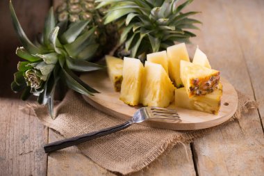 Ananas dilimleri ve eski ahşap arka plan üzerinde kabuklu ananas