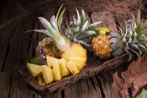 Pineapple slices and pineapple shelled on old wooden background