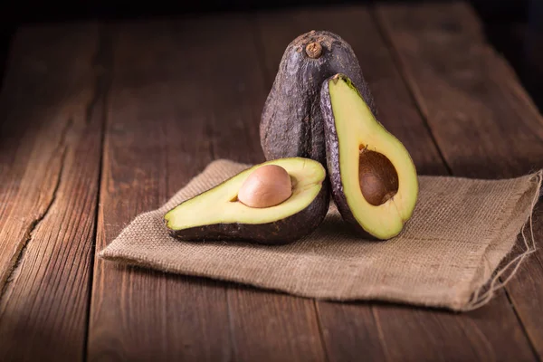 Halved avocado on a rustic table. Fresh avocado on black backgro — Stock Photo, Image