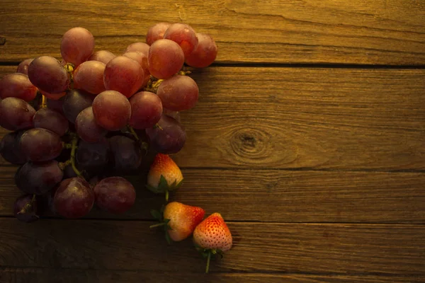 木製の背景にブドウとイチゴのトップ ビュー — ストック写真