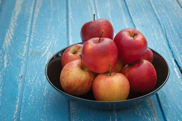 Mavi ahşap masa üzerinde taze Olgun kırmızı elmalar