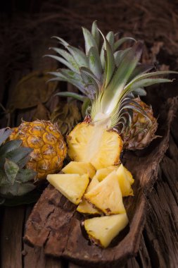 Ananas dilimleri ve eski ahşap arka plan üzerinde kabuklu ananas
