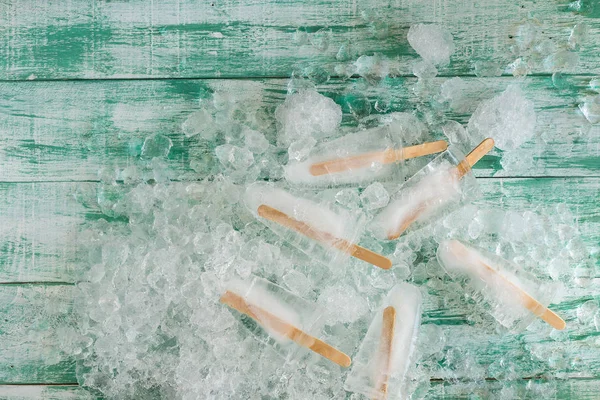 Ice crushed on green wooden background and ice in a black tray