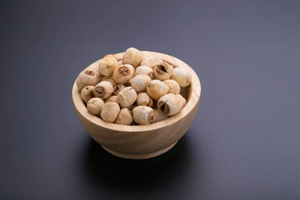 Dry lotus seeds in wooden bowl on black background — Stock Photo, Image