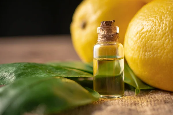 Flessen met etherische olie van citroen schil en bladeren op houten tabl — Stockfoto