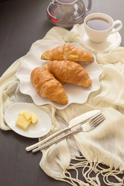 Taze pişmiş kruvasanlar ve çay bir da üzerinde beyaz bir plaka üzerinde