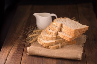 Kupa süt ile ahşap tabloda kepekli ekmek dilimlenmiş