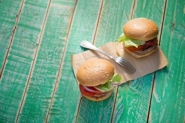 Peynirli hamburger ızgara et, peynir, domates yeşil Ahşap yüzeyi ile