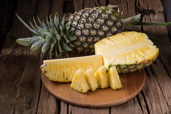 Ananas dilimleri ve eski ahşap arka plan üzerinde kabuklu ananas