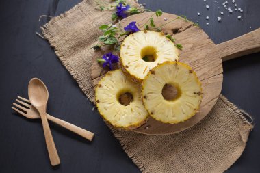 Ananas dilimleri ve eski ahşap arka plan üzerinde kabuklu ananas