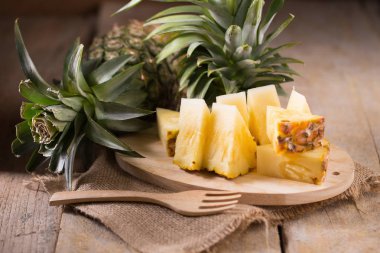 Ananas dilimleri ve eski ahşap arka plan üzerinde kabuklu ananas