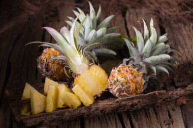 Ananas dilimleri ve eski ahşap arka plan üzerinde kabuklu ananas