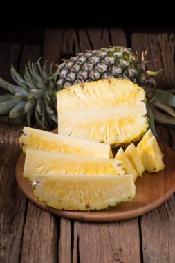 Ananas dilimleri ve eski ahşap arka plan üzerinde kabuklu ananas