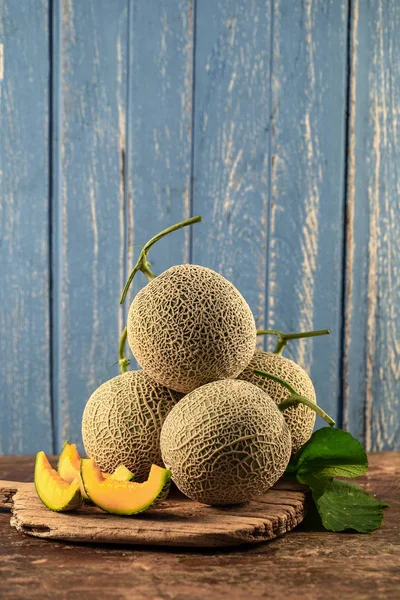 Food composition of cantaloupe melons on wooden table with shabby wooden background