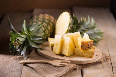 Ananas dilimleri ve eski ahşap arka plan üzerinde kabuklu ananas