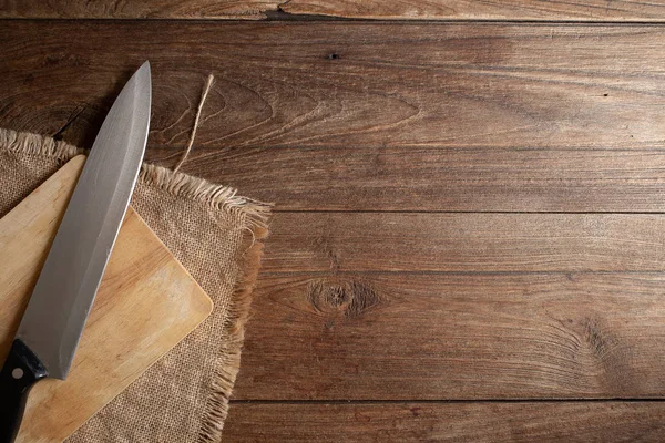 knife and wooden chopping board on dark old wooden table