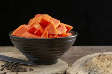 Olgun papaya meyve ahşap arka plan üzerinde siyah kase parçaları