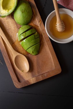 Taze bal ile organik avokado siyah ahşap arka plan üzerine dilimlenmiş.
