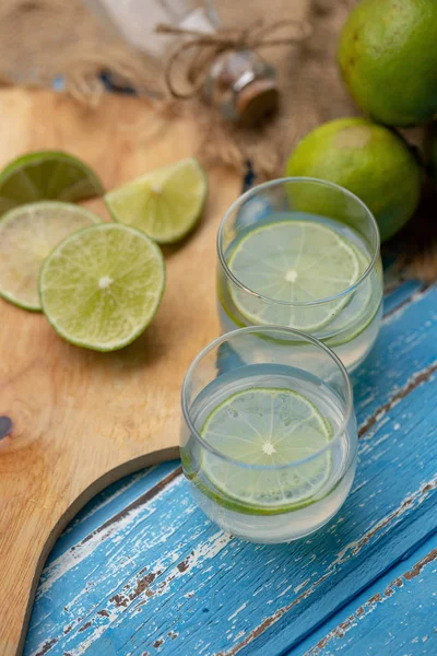 Lime juice and fresh limes on blue wooden table