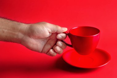 Erkek el kırmızı kahve fincanı kırmızı zemin üzerine tutarak