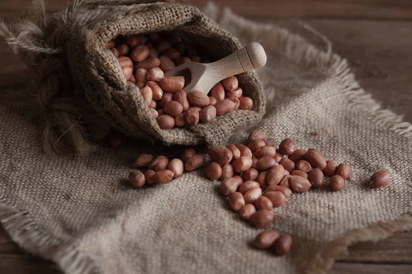 Peanuts seed in sackcloth bag on wooden table.