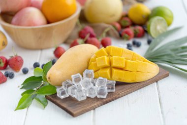 Ahşap plaka buz küpleri ve arka plan üzerinde meyve olgun Mango