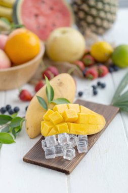 Ahşap plaka buz küpleri ve arka plan üzerinde meyve olgun Mango