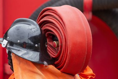 Bir rulo kırmızı yangın hortumu haddelenmiş, yangın söndürme cihazları kullanıma hazır.