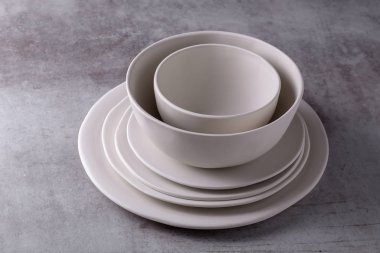 Boş boş beyaz seramik tabak ve çimento tahtada beyaz seramik kase.