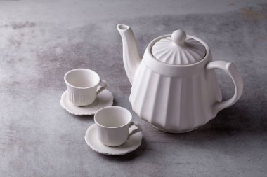 Çaydanlık kreması, fincan ve çay tabağı çimento tahtasında..