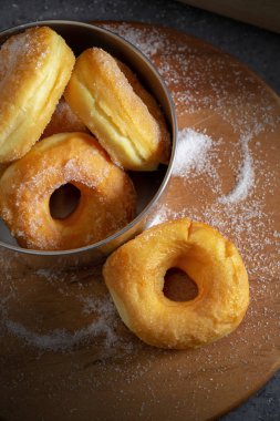 Koyu bir masa arkasındaki tahta tabakta şekerli çörekler.