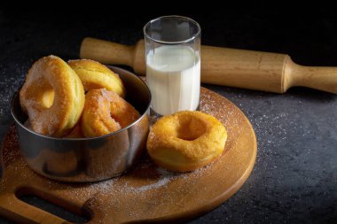 Koyu bir masa arkasındaki tahta tabakta şekerli çörekler.