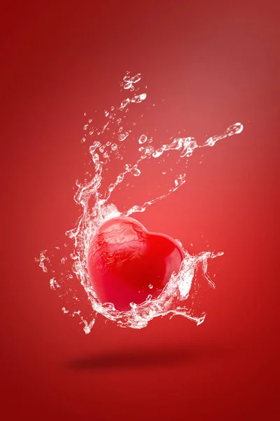 Разбрызгивание воды на пену из красного шара с формой сердца на красной спине — стоковое фото