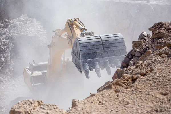 Ekskavator kuning mengisi sebuah truk dump dengan batu di tambang batubara — Stok Foto