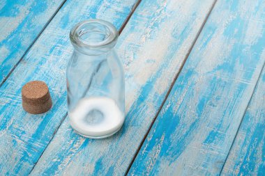 kahvaltıdan sonra mavi ahşap bir masaya boş süt şişesi