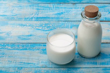 Mavi ahşap bir masada bir şişe süt ve bir bardak süt, healt