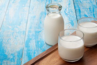 Mavi ahşap bir masada bir şişe süt ve bir bardak süt, healt