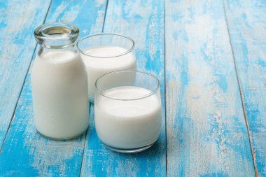 Mavi ahşap bir masada bir şişe süt ve bir bardak süt, healt