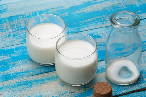 Eine Flasche Milch und ein Glas Milch auf einem blauen Holztisch, — Stockfoto